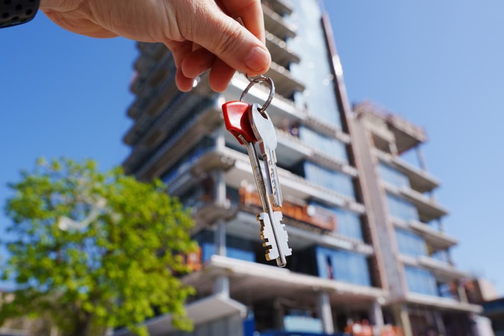 Someone holding a set of keys in front of an apartment building